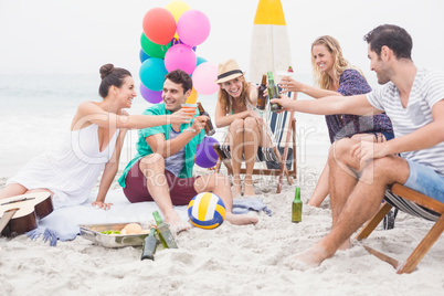 Group of friends toasting beer bottles on the beach