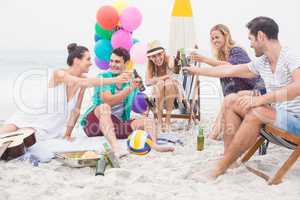 Group of friends toasting beer bottles on the beach
