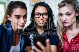 Beautiful female friends looking in mobile phone