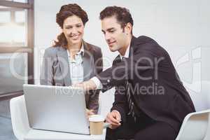 Businessman explaining female colleague over laptop