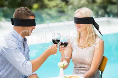 Blindfolded couple toasting red wine while