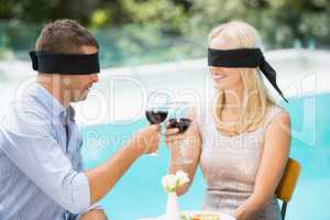 Blindfolded couple toasting red wine while