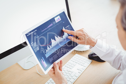 Businesswoman pointing on graph at computer desk