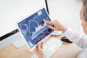 Businesswoman pointing on graph at computer desk