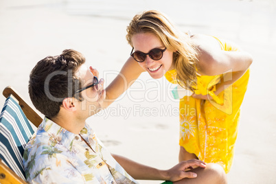 Happy woman applying moisturizer on mans nose