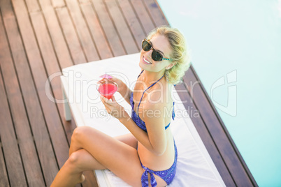Portrait of beautiful woman with cocktail sitting on sun lounger