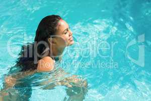 Beautiful woman in white bikini swimming in swimming pool