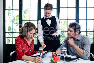 Waitress assisting a couple while selecting menu