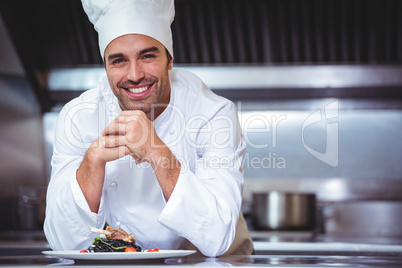 Chef leaning on the counter with a dish