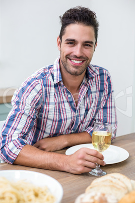 Handsome young man drinking wine at table