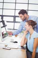 Businessman pointing at computer while explaining female colleag