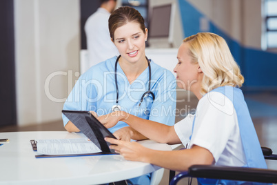 Female doctors using digital tablet while discussing