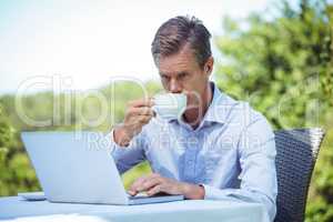 Businessman using laptop with coffee