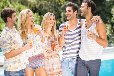 Group of happy friends having juice near pool