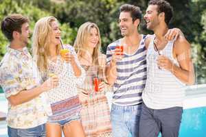 Group of happy friends having juice near pool