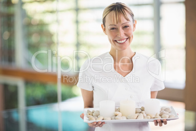 Portrait of smiling female masseur holding tray