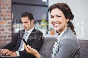 Businesswoman using cellphone while colleague in background