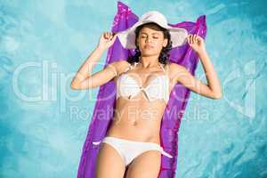 Woman in white bikini lying on air bed in po