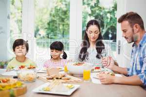Family with eyes closed while sitting at dining table