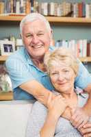 Portrait of happy senior couple against bookshelf at home