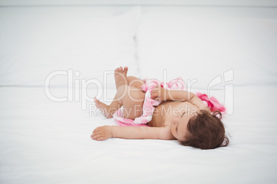 Baby holding blanket while lying on bed
