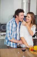 Smiling beautiful wife feeding husband in kitchen