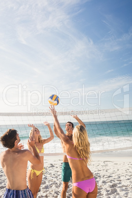 Happy friends playing beach volleyball