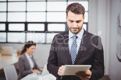 Businessman using digital tablet while colleague in background