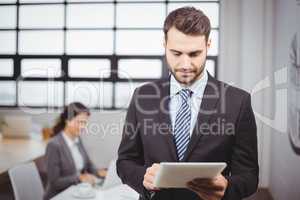 Businessman using digital tablet while colleague in background