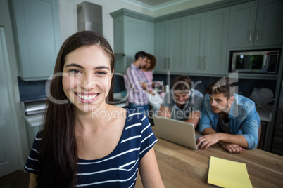 Happy young woman with friends in background at home