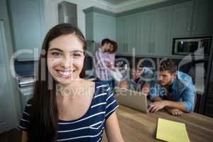 Happy young woman with friends in background at home