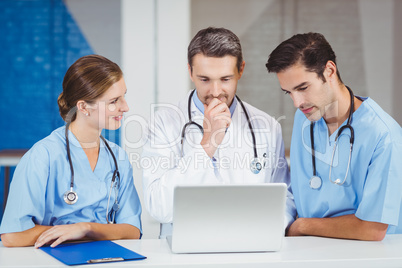 Doctors using laptop while standing at desk