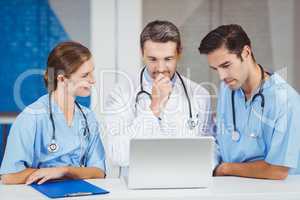 Doctors using laptop while standing at desk