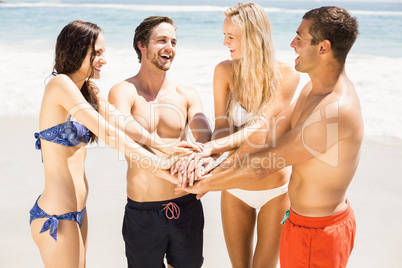 Young friends putting their hands together on the beach