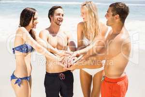 Young friends putting their hands together on the beach