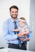 Cheerful businessman carrying daughter by table