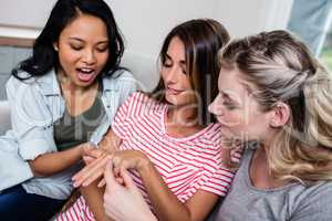 Young woman showing engagement ring to friends