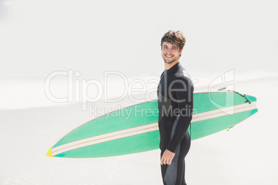 Happy man holding surfboard on the beach