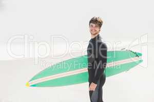 Happy man holding surfboard on the beach