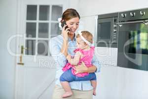 Woman talking on cellphone while carrying baby girl