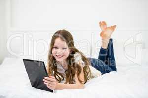 Portrait of girl using digital tablet on bed