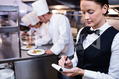 Waitress with note pad in commercial kitchen
