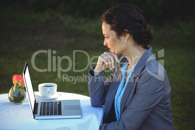 Businesswoman using laptop with coffee