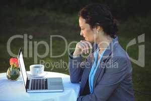 Businesswoman using laptop with coffee