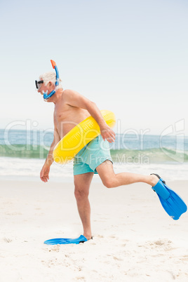 Senior man with swimming ring and flippers at the beach
