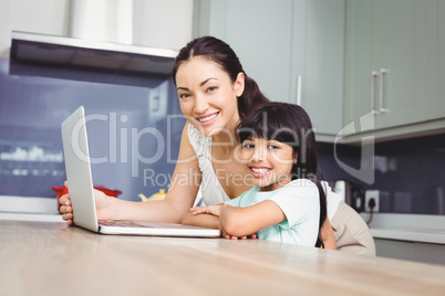 Portrait of happy mother and daughter working on laptop