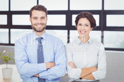 Happy business people with arms crossed in office