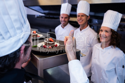 Head chef showing his thumbs up after inspecting dessert plates