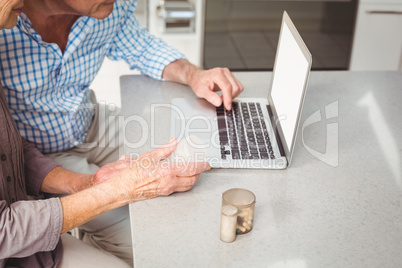 Cropped image of senior couple searching for pills on laptop