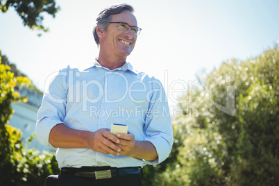 Casual businessman smiling using smartphone